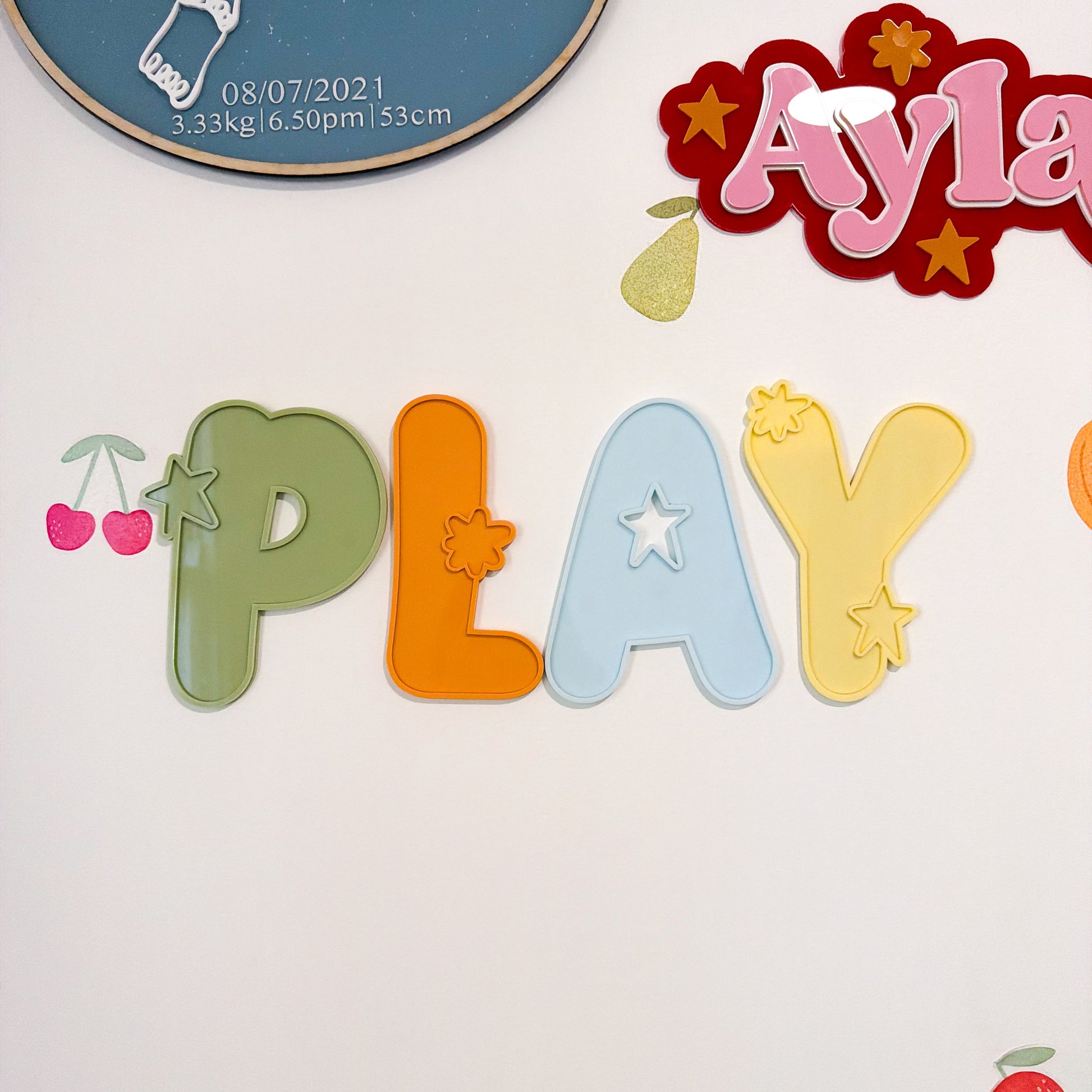 Colorful cut-out letters spelling 'PLAY' on a white background with decorative elements.