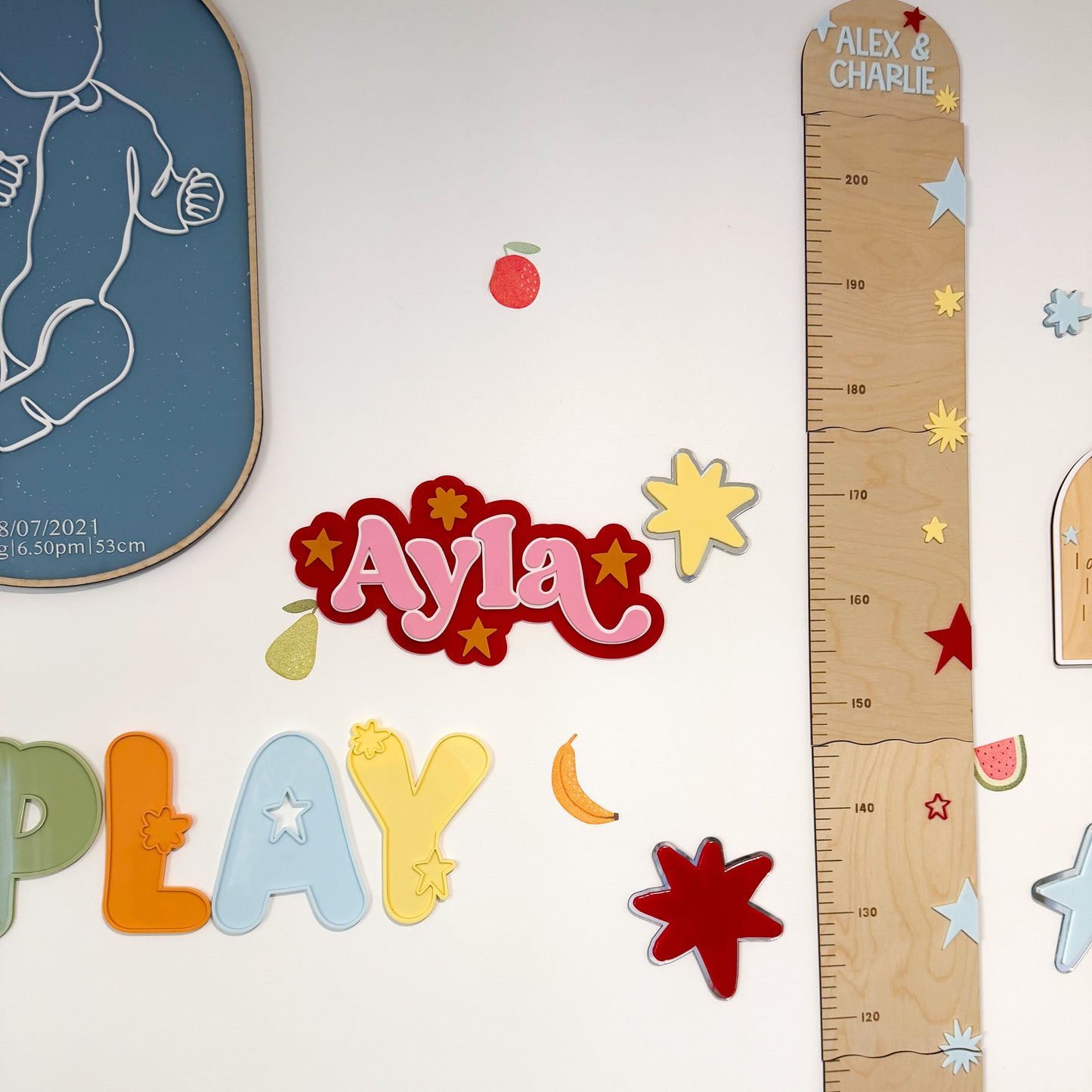 Children's room decor with a growth chart, colorful letters, and stickers on a white wall.